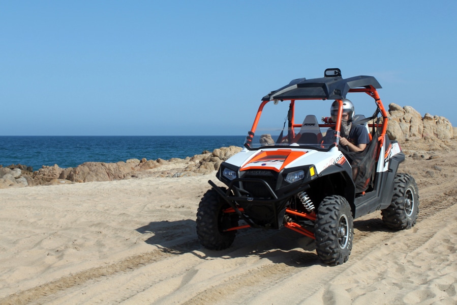 ATV riders on Cabo desert trail with ocean view in background